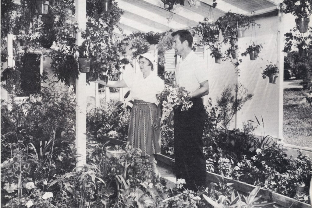 black and white photo of two people standing in a garden room