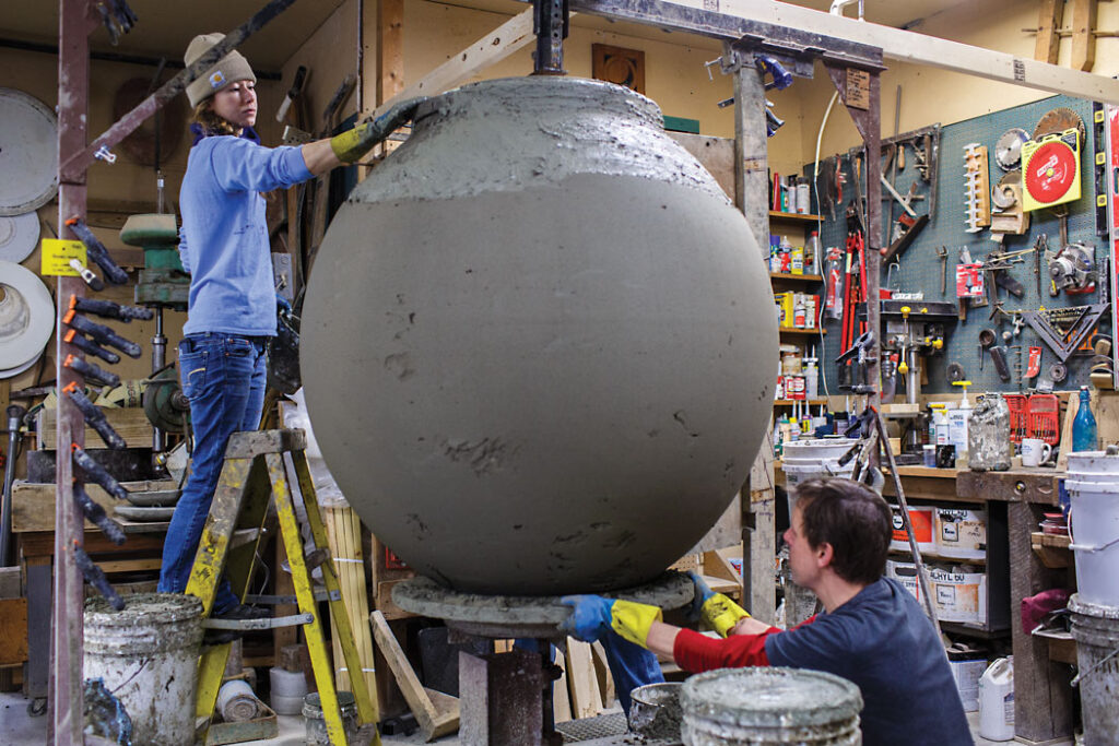 People working on large clay urn