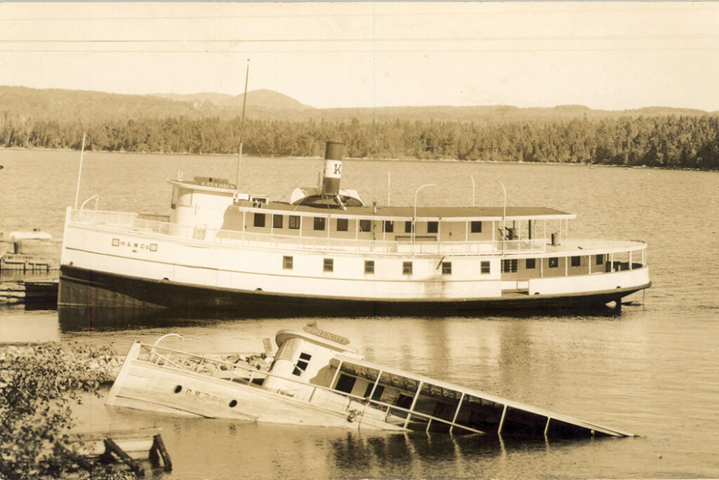 old photo of a steamboat next to another sinking steamboat on Moosehead Lake