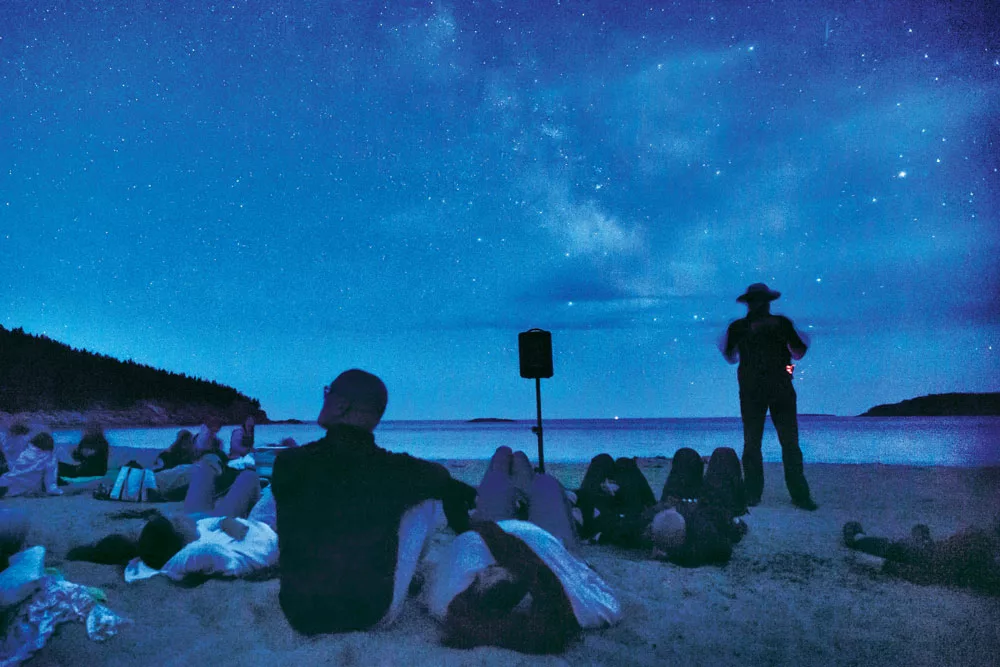 An Acadia National Park ranger takes visitors on a celestial journey at Sand Beach