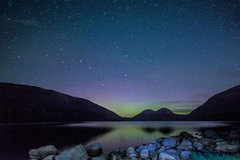 On a cloudless night, the night sky can be seen reflected in the still waters of Jordan Pond in Acadia National Park